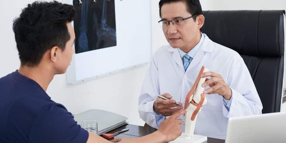 Pain Specialist Holds a Model While Explaining Pain Management Treatment Options